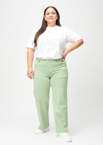 Full image of a plus-size model in light green loose jeans.
