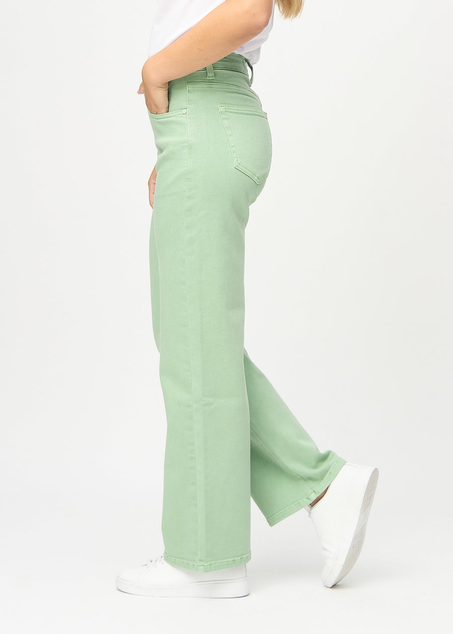 Light green loose jeans seen from the side on a model.
