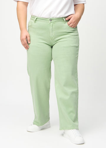 Light green loose jeans, model name Mints, which are loose-fitting with plenty of width in the legs on a plus-size model, seen from the front.
