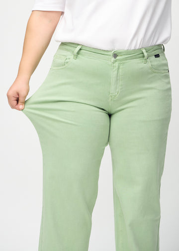 The plus-size model stretches the jeans at the thigh to show the stretch.
