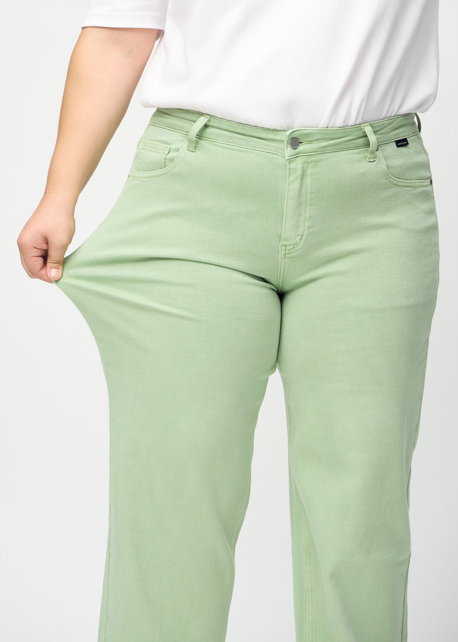 The plus-size model stretches the jeans at the thigh to show the stretch.
