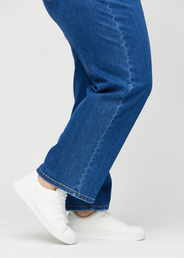 Loose jeans for women in dark blue, color Oceans. Close-up at the ankles on a plus-size model, showing the wide leg openings.