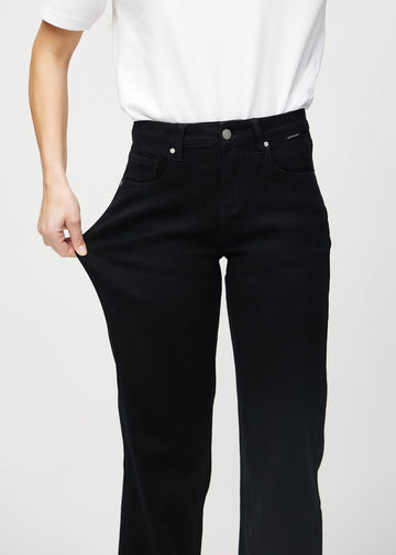 Loose jeans for women in black, color Ravens. A model stretches the denim at the thigh to show the fabric&