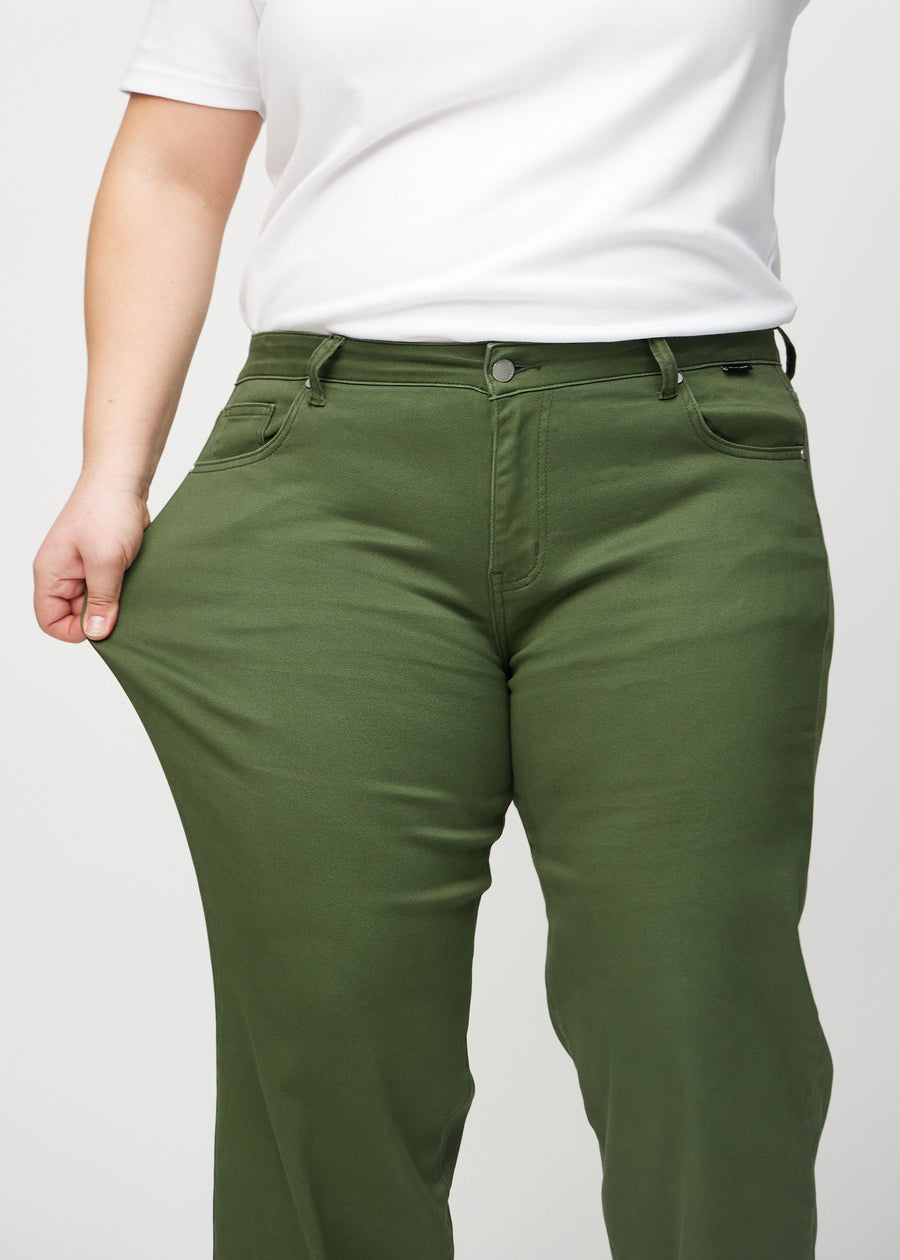 The plus-size model stretches the jeans at the thigh to show the stretch.