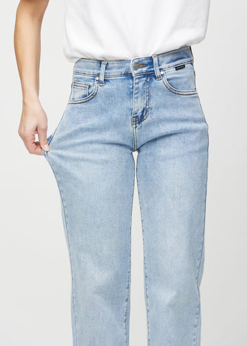 The model stretches the jeans at the thigh to show the stretch.
