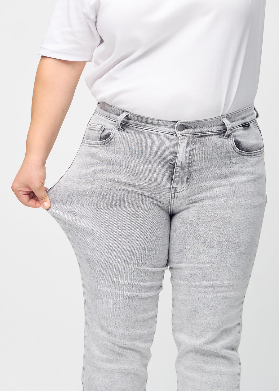 Regular jeans for women in light grey, color Ashes. A plus-size model stretches the fabric at the thigh to show its stretch.