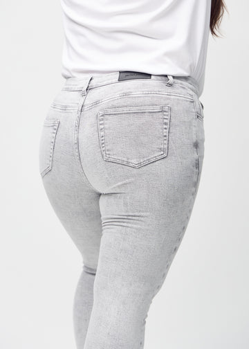 Light grey denim skinny jeans seen from the back close up on a plus-size model to show details.