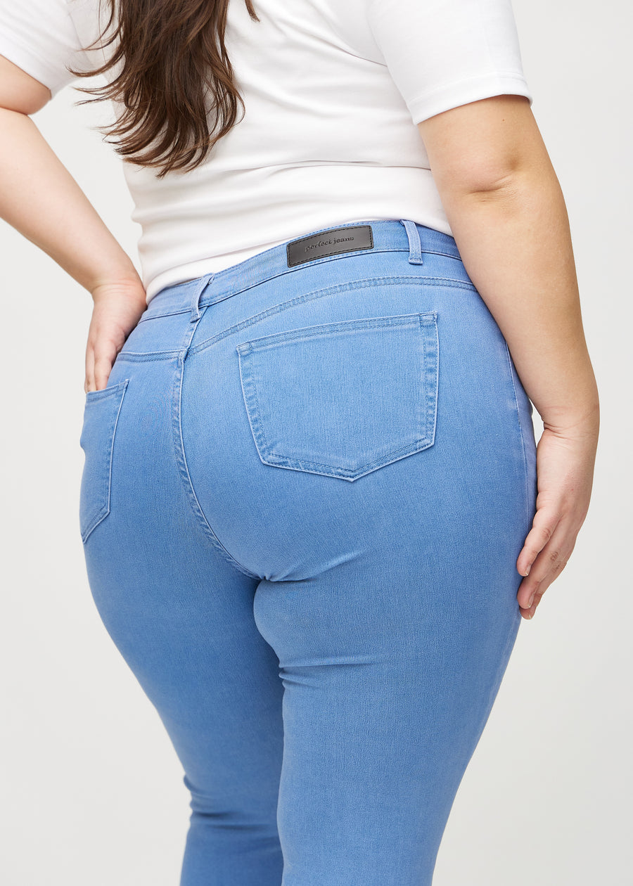 Blue skinny jeans seen from the back close up on a plus-size model to show details.