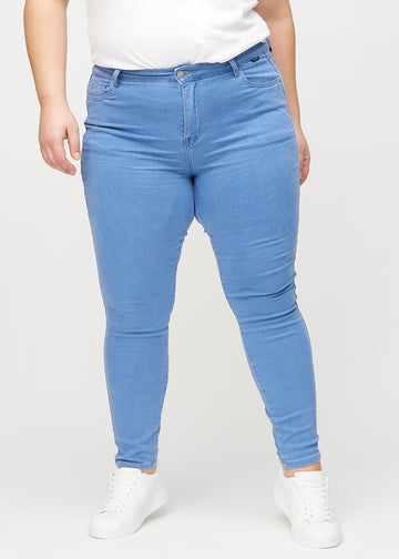 Blue skinny jeans, model name Geraniums, which fits closely to the leg on a plus-size model, seen from the front.