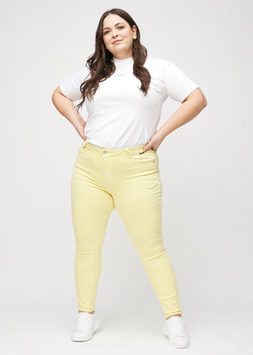 Skinny jeans for women in light yellow, color Lemonades. Full-length view of a plus-size model in the jeans.