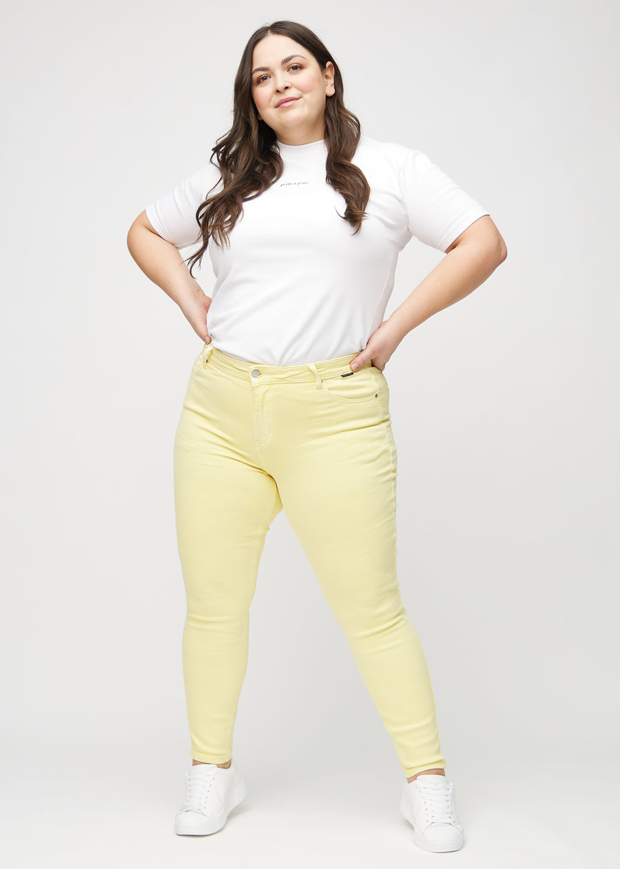 Skinny jeans for women in light yellow, color Lemonades. Full-length view of a plus-size model in the jeans.