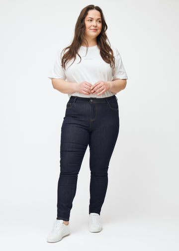Full image of a plus-size model in deep dark blue denim jeans for women in the color Midnights with a skinny fit.