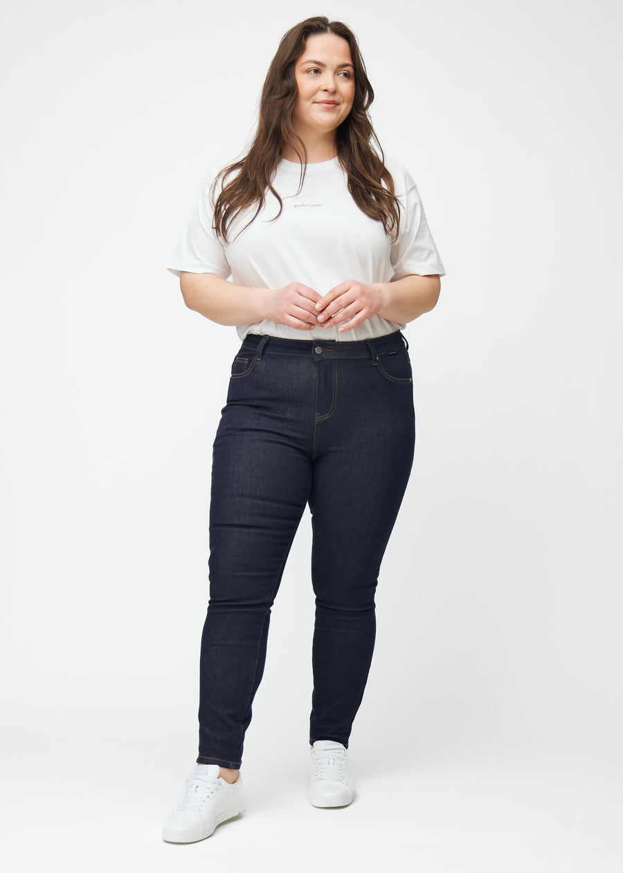 Full image of a plus-size model in deep dark blue denim jeans for women in the color Midnights with a skinny fit.