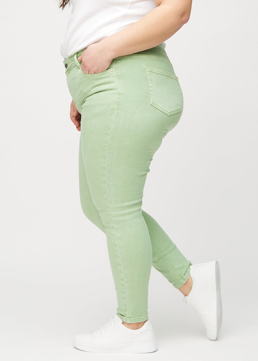 Skinny jeans for women in light green, color Mints. Side view on a plus-size model.