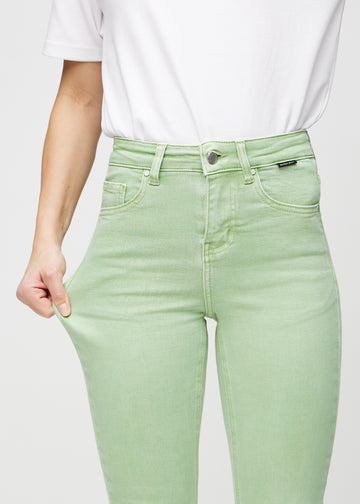 Skinny jeans for women in light green, color Mints. A model stretches the jeans at the thigh to show the fabric&