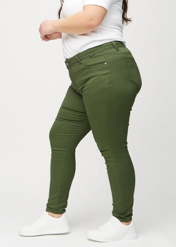 Dark green skinny jeans seen from the side on a plus-size model.