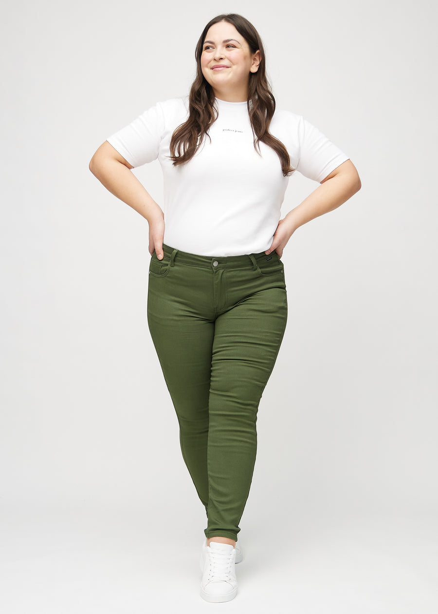 Full image of a plus-size model in dark green skinny jeans.