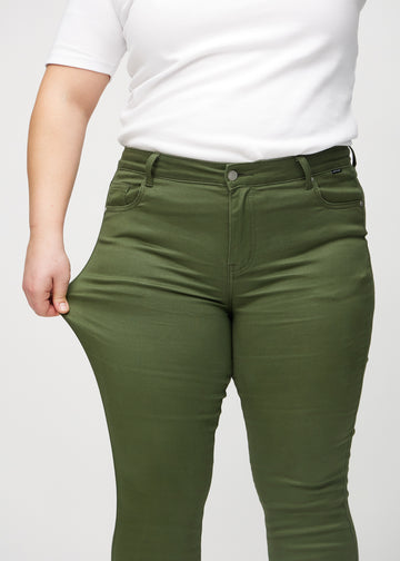 The plus-size model stretches the jeans at the thigh to show the stretch.