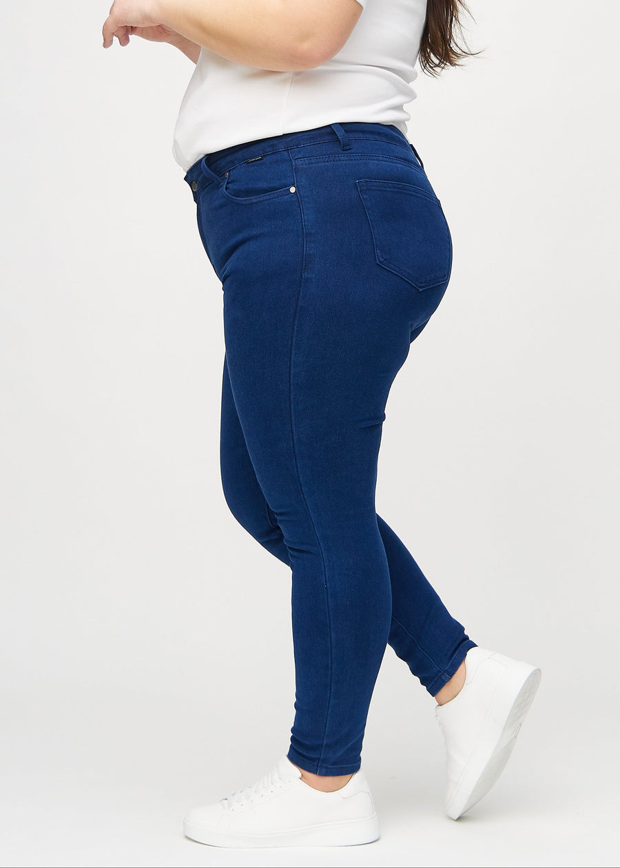 Dark blue skinny jeans viewed from the side on a plus-size model.