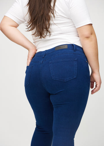 Dark blue skinny jeans viewed from the back close up on a plus-size model to show details.