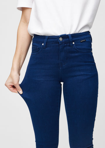 The model stretches the jeans at the thigh to show the stretch.