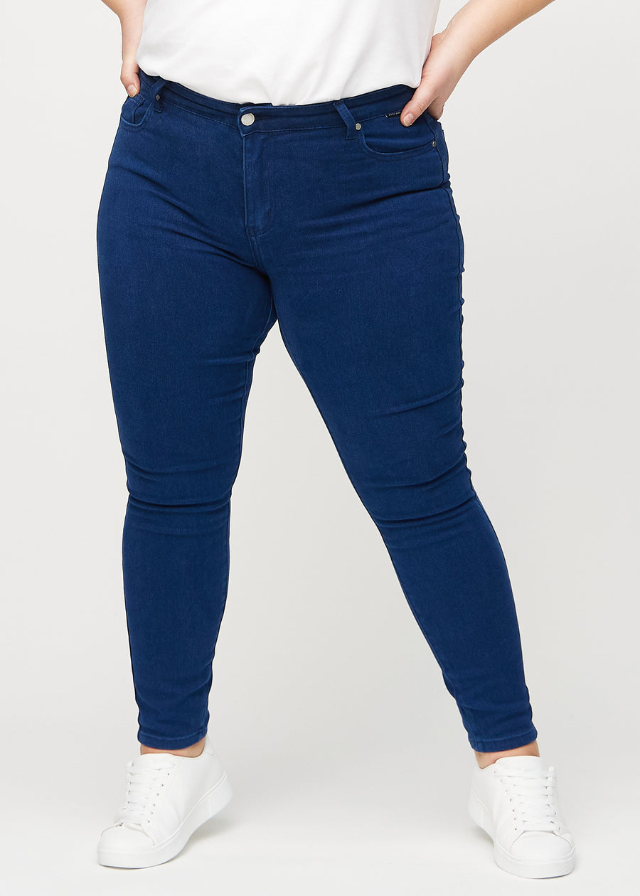 Dark blue skinny jeans, model name Royals, which fits closely to the leg on a plus-size model, viewed from the front.