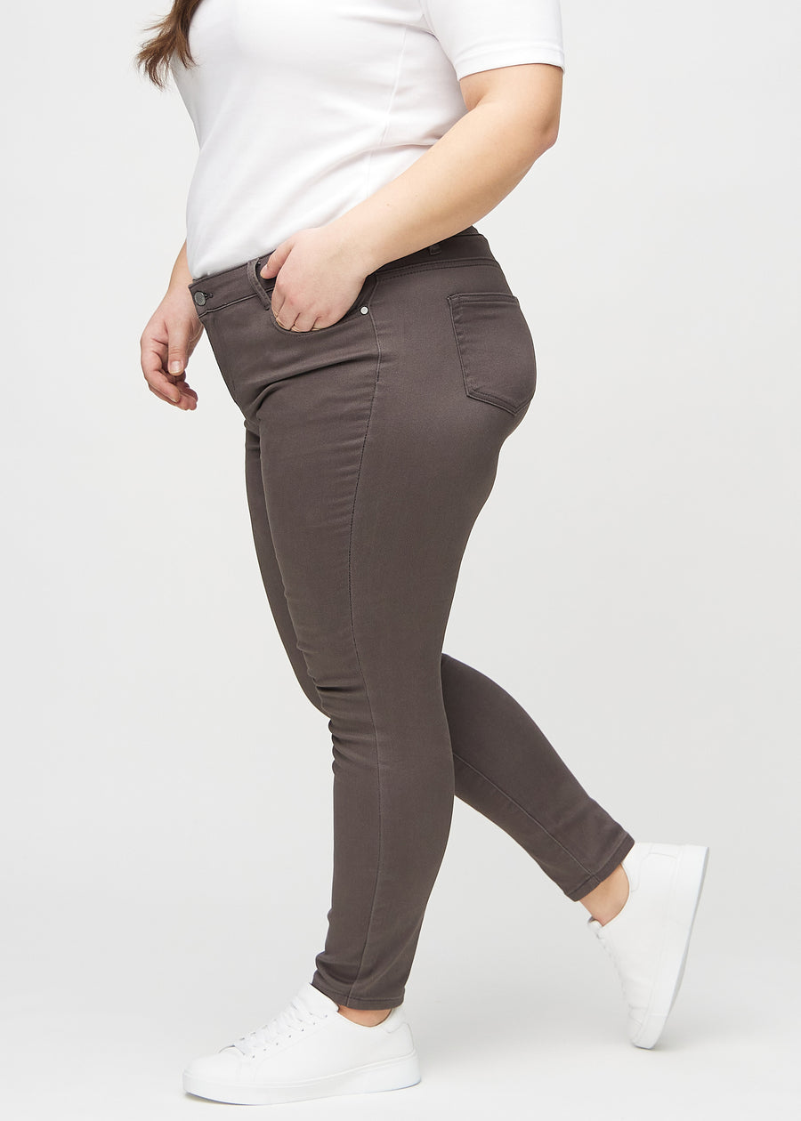 Grey-brown skinny jeans seen from the side on a plus-size model.