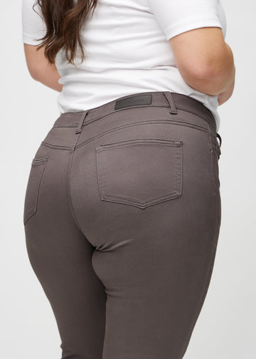 Grey-brown skinny jeans seen from the back close up on a plus-size model to show details.
