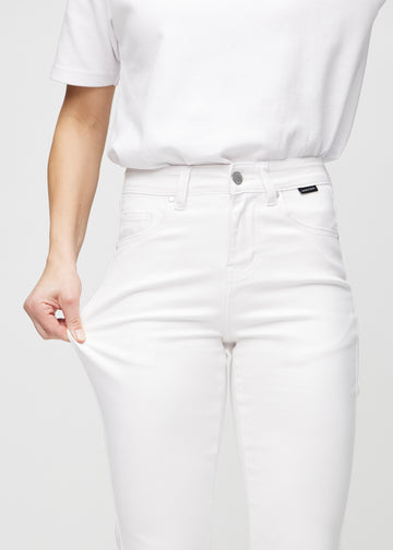 Slim jeans for women in white, color Marguerites. A model stretches the jeans at the thigh to show the fabric&
