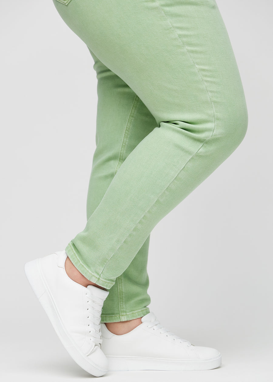 Slim jeans for women in light green, color Mints. Close-up at the ankles on a plus-size model, showing the fit at the leg openings.