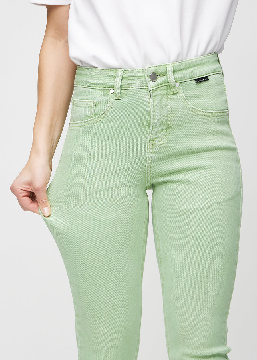 Slim jeans for women in light green, color Mints. A model stretches the jeans at the thigh to show the fabric&