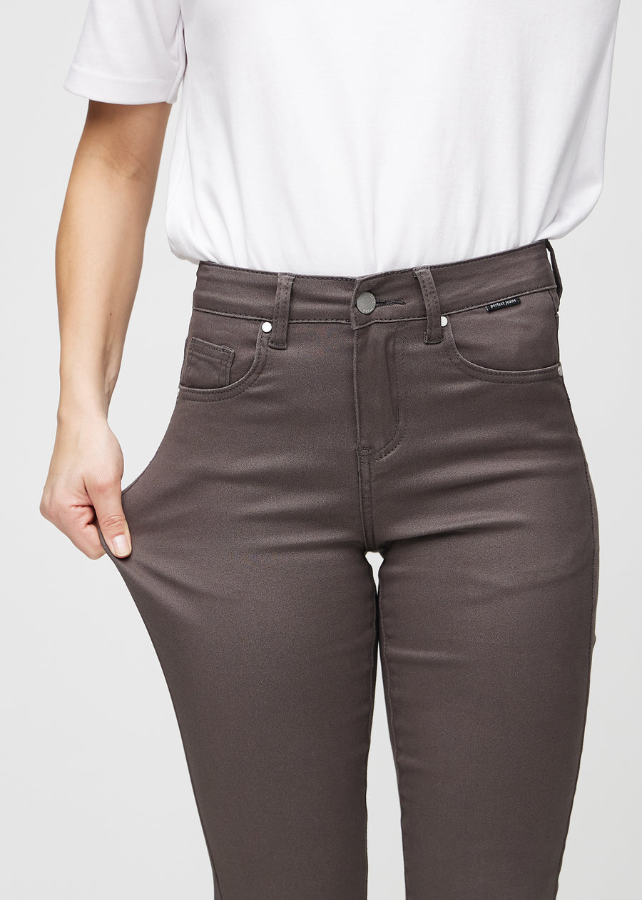 Slim jeans for women in grey-brown, color Thunders. A model stretches the jeans at the thigh to show the fabric&