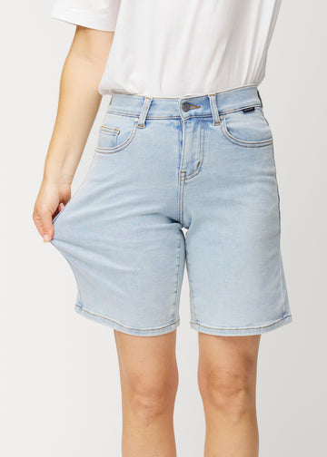 Model stretches the light blue Waves denim shorts at the thigh to show the fabric&