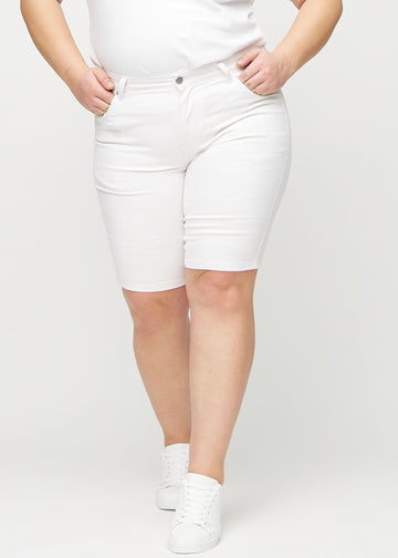 White skinny middle shorts, model name Marguerites, which fit tightly around the thigh and end just above the knee on a plus-size model, seen from the front.