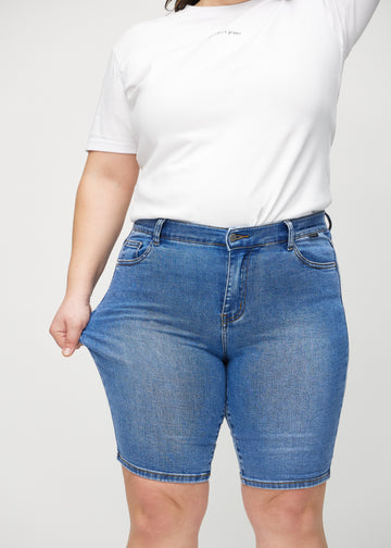 The plus-size model stretches the shorts at the thigh to show the stretch.