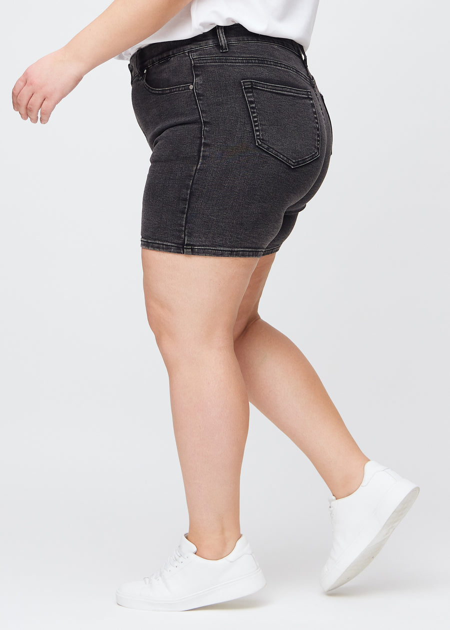 Dark grey denim skinny short shorts seen from the side on a plus-size model.
