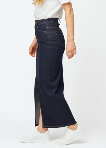 Long deep dark blue denim skirt for women in the colour Midnights seen from the side on a model, with a visible front slit.
