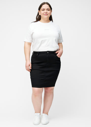 Fuldt billede af plus-size model i sort, tætsiddende og knælang jeansnederdel.