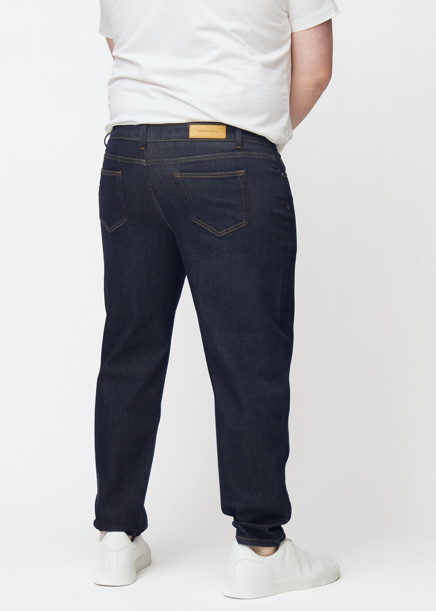 Deep dark blue denim jeans for men in the color Midnights seen from the back on a plus-size model.