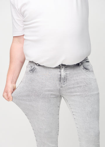 Plus-size model stretches the jeans at the thigh to show the fabric&