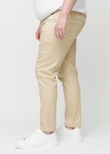Beige slim jeans viewed from the side on a plus-size model.