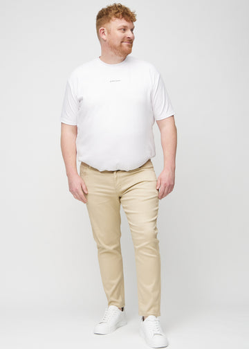 Full-length view of a plus-size model in beige slim jeans.