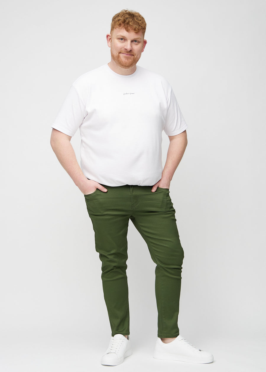 Full-length view of a plus-size model in dark green slim jeans.