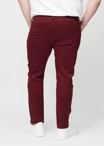Dark red slim jeans viewed from the back on a plus-size model to show the full product.