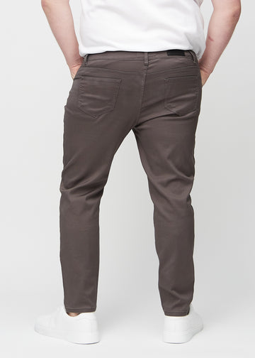 Grey-brown slim jeans viewed from the back on a plus-size model to show the full product.