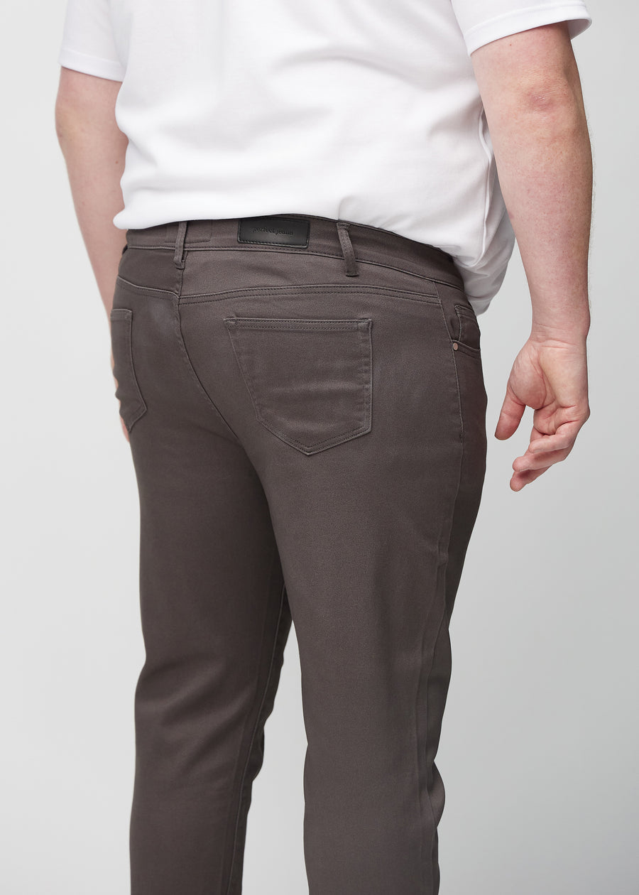 Close-up back view of grey-brown slim jeans on a plus-size model showing details.