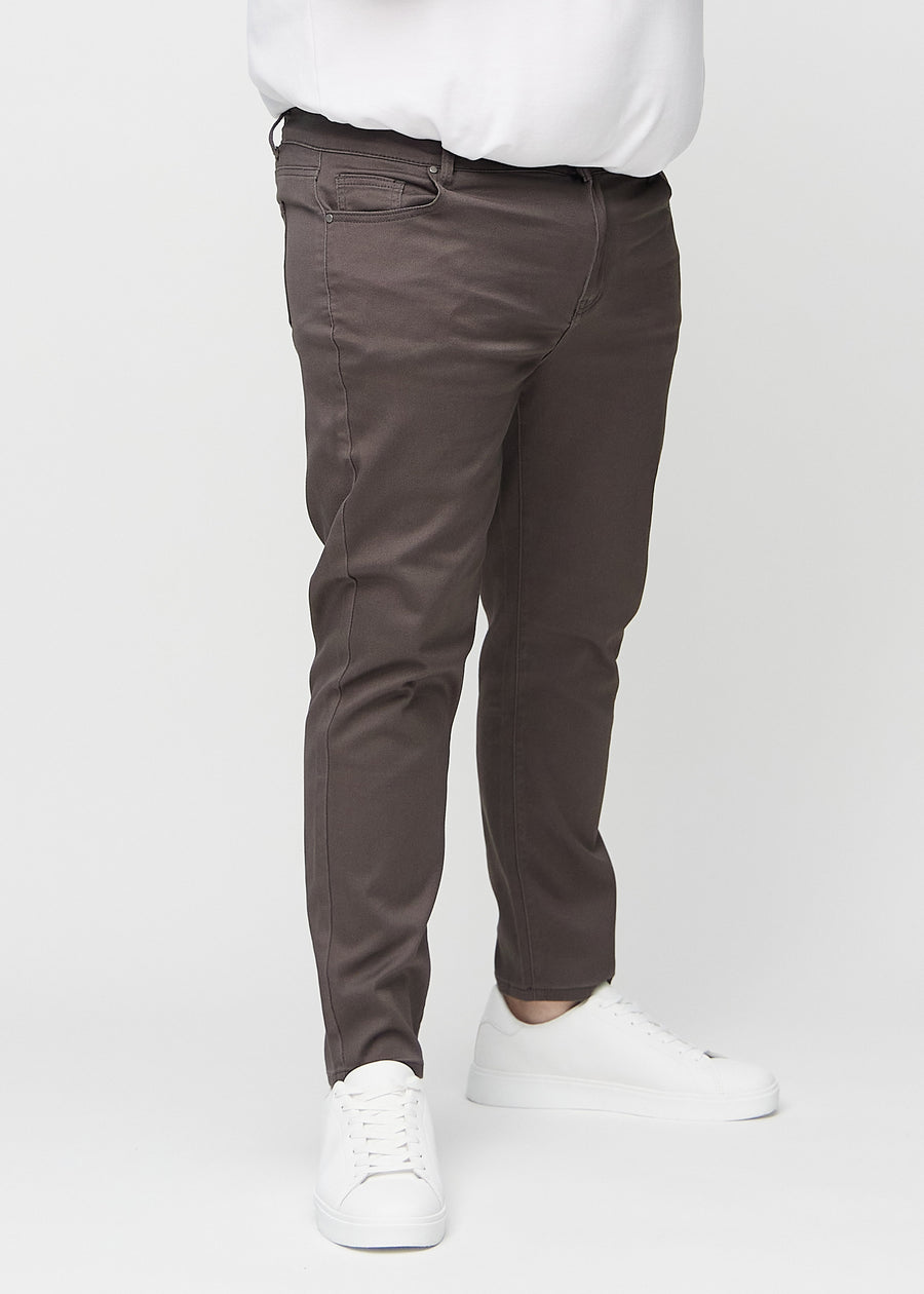 Grey-brown slim jeans, model name Thunders, fitted closely along the legs on a plus-size model, front view.