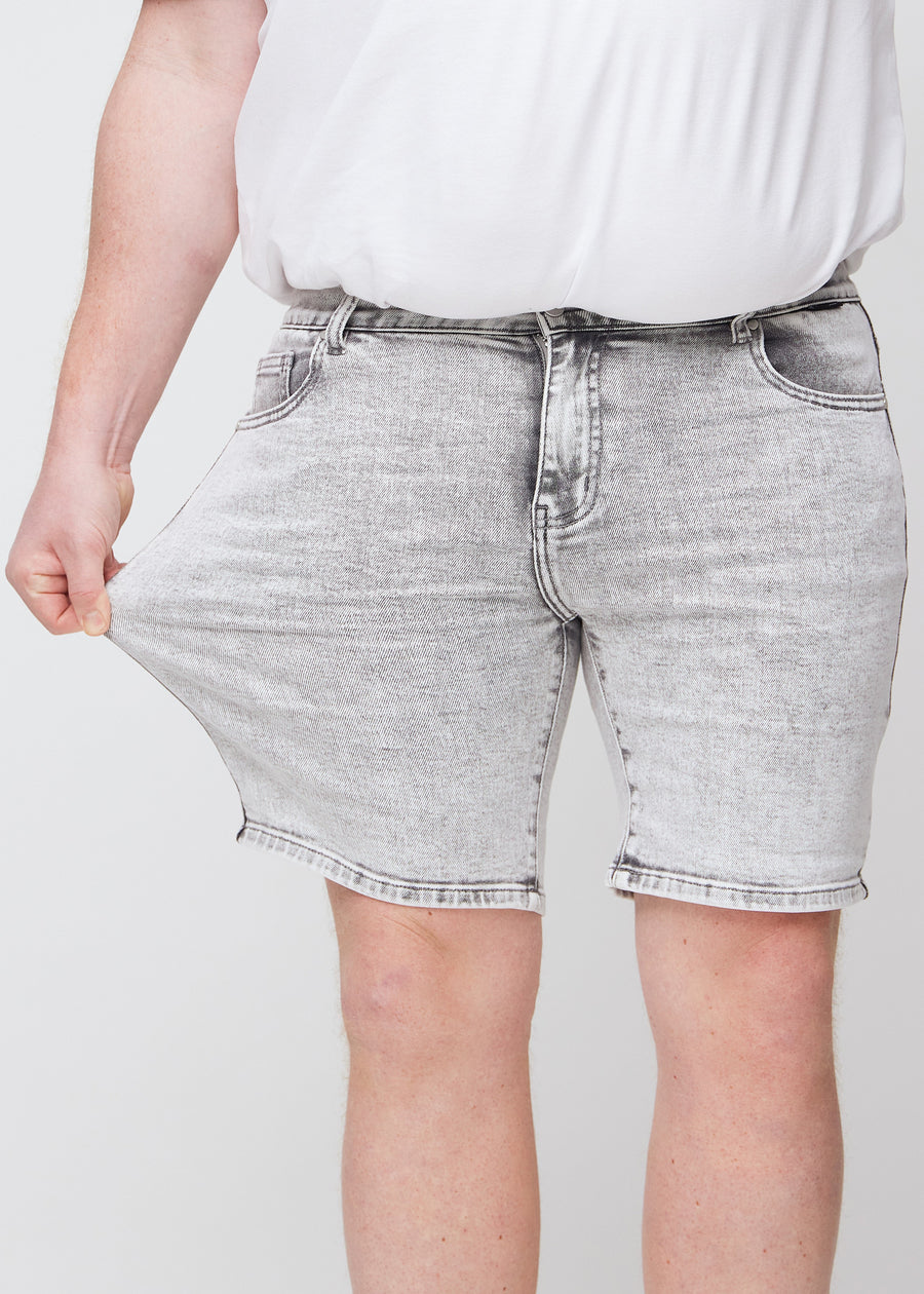 The plus-size model stretches the shorts at the thigh to show the stretch.