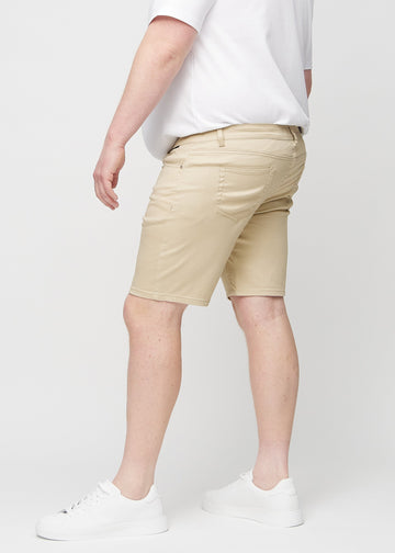 Beige middle-slim shorts seen from the side on a plus-size model.