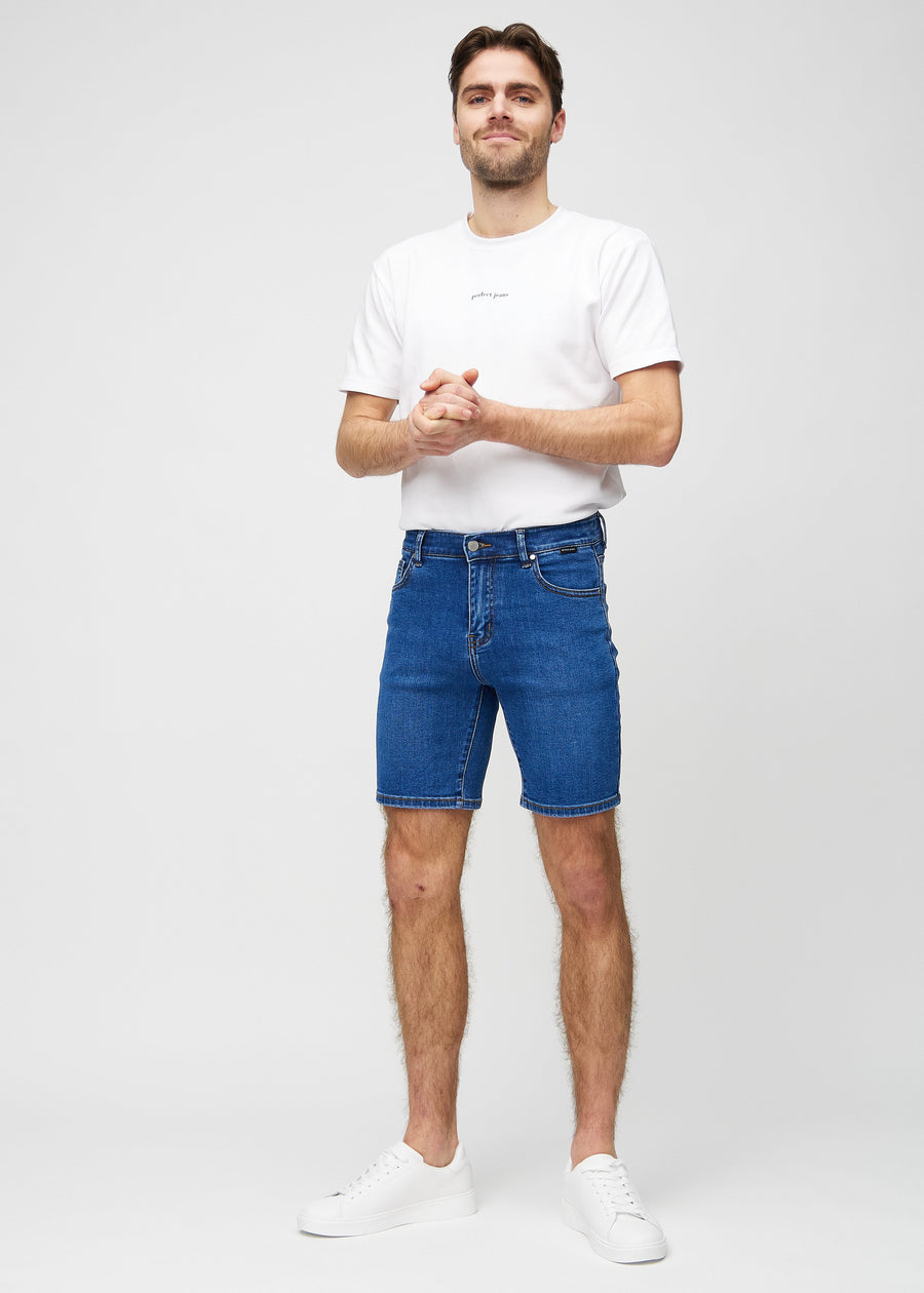 Full image of a model in dark denim middle-slim shorts.